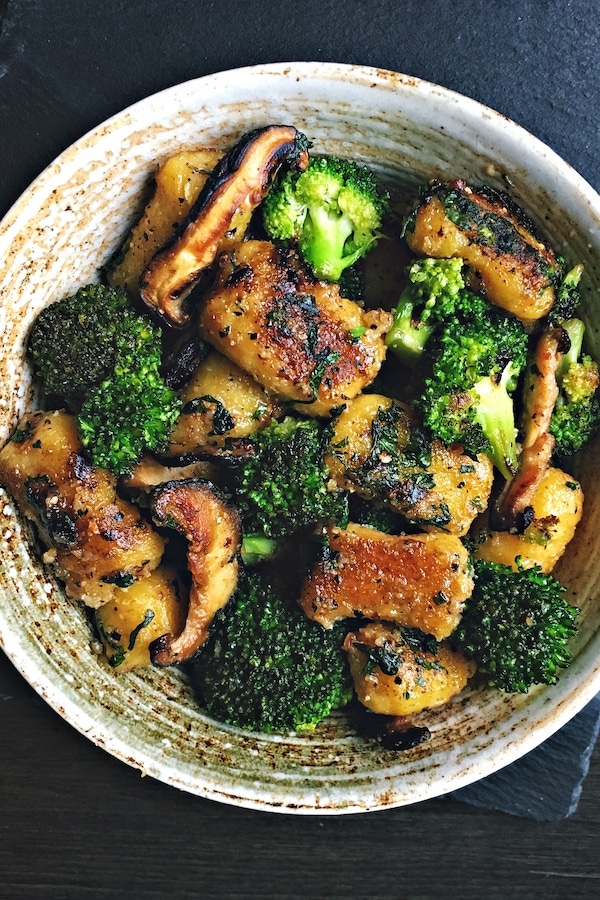 pan-stegt vegansk gnocchi med broccoli og svampe i en skål