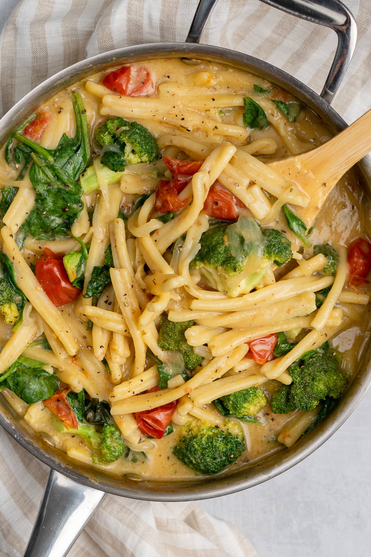 Pasta with vegetables in a pot with wooden spoon