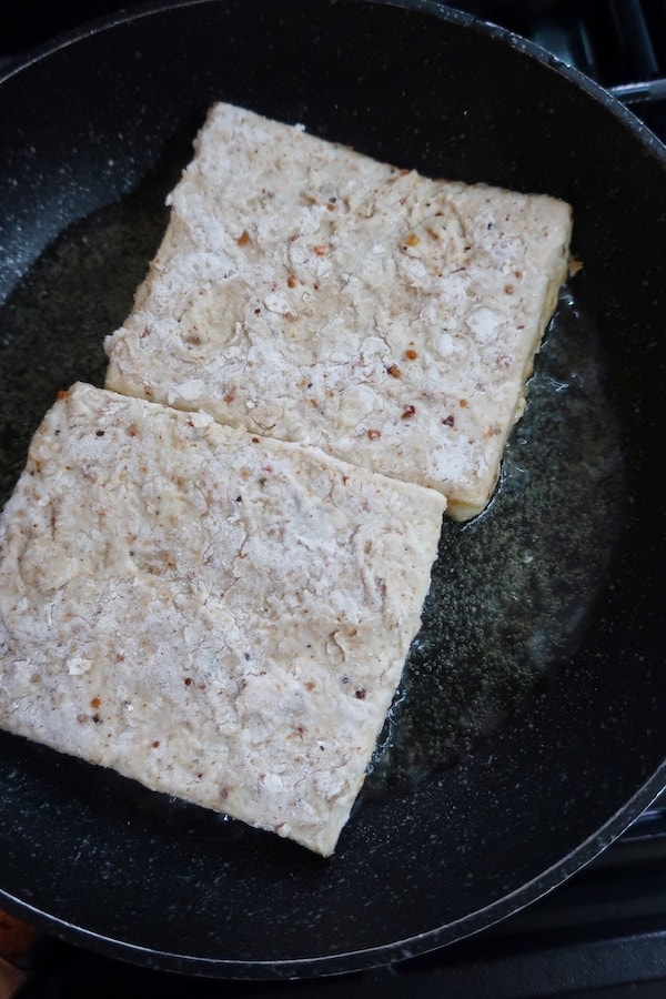 Flour coated seasoned tofu in frying pan
