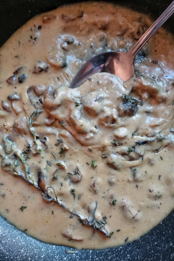 close up of vegan mushroom gravy in skillet with spoon