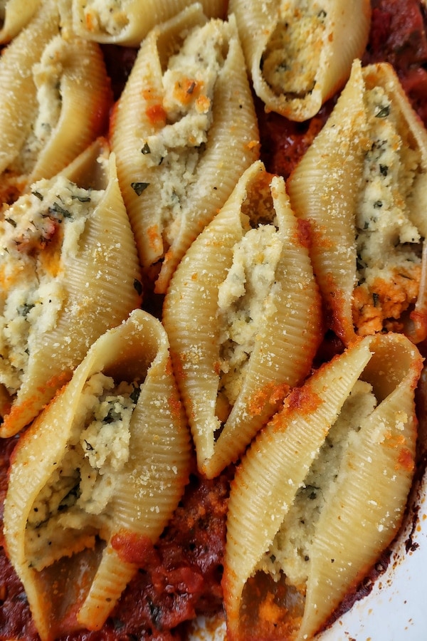 Close up of vegan stuffed pasta shells with almond ricotta in white casserole dish