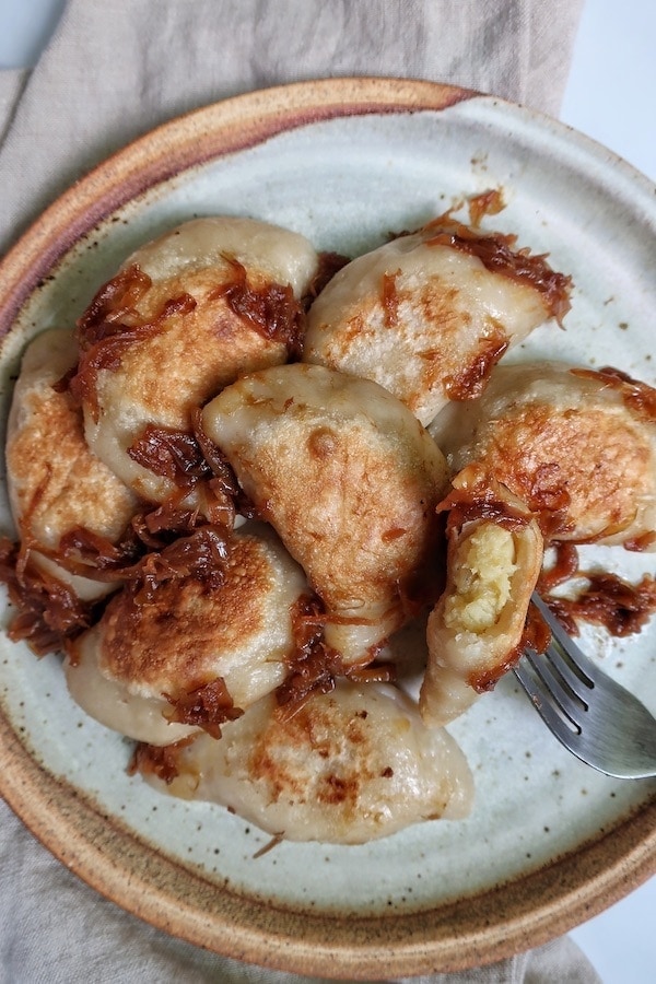 Vegan pierogies on plate with one cut open showing filling
