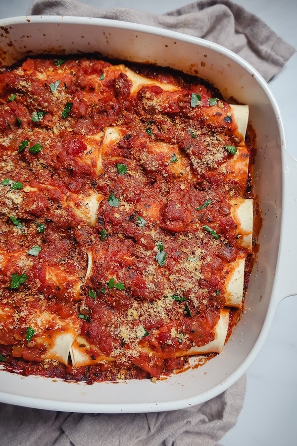 Baked vegan cannelloni in a casserole dish on a towel