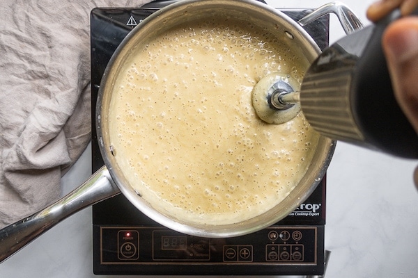 Μπλέντερ εμβάπτισης σε τηγάνι που αναμειγνύει vegan σάλτσα αλφρέντο