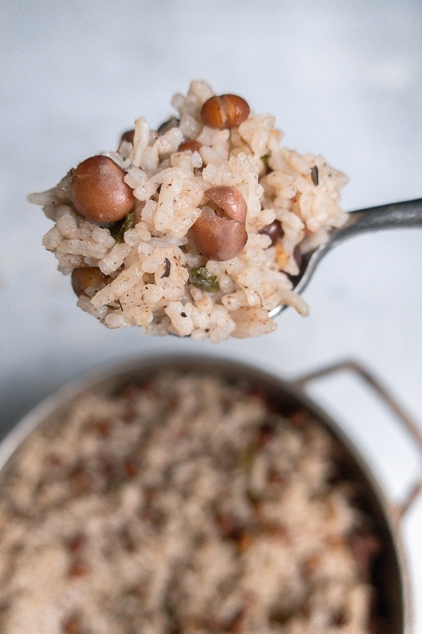 Pigeon peas and rice on a spoon over a pot