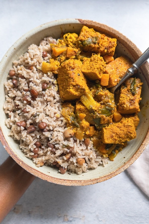 Jamaican pigeon peas and rice with tofu curry in a bowl with a spoon