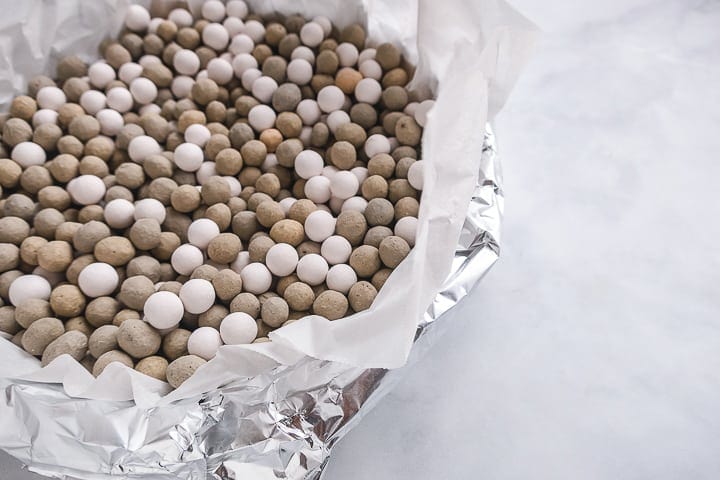 Weighted balls on parchment paper in pie crust lined with foil