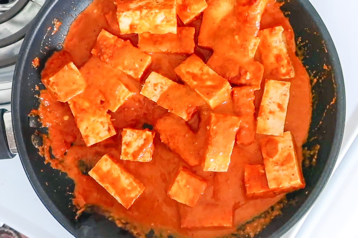 Tofu in red curry sauce in a pan