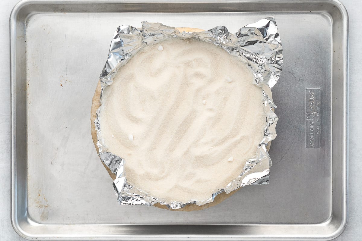 Unbaked pie dough filled with foil and sugar