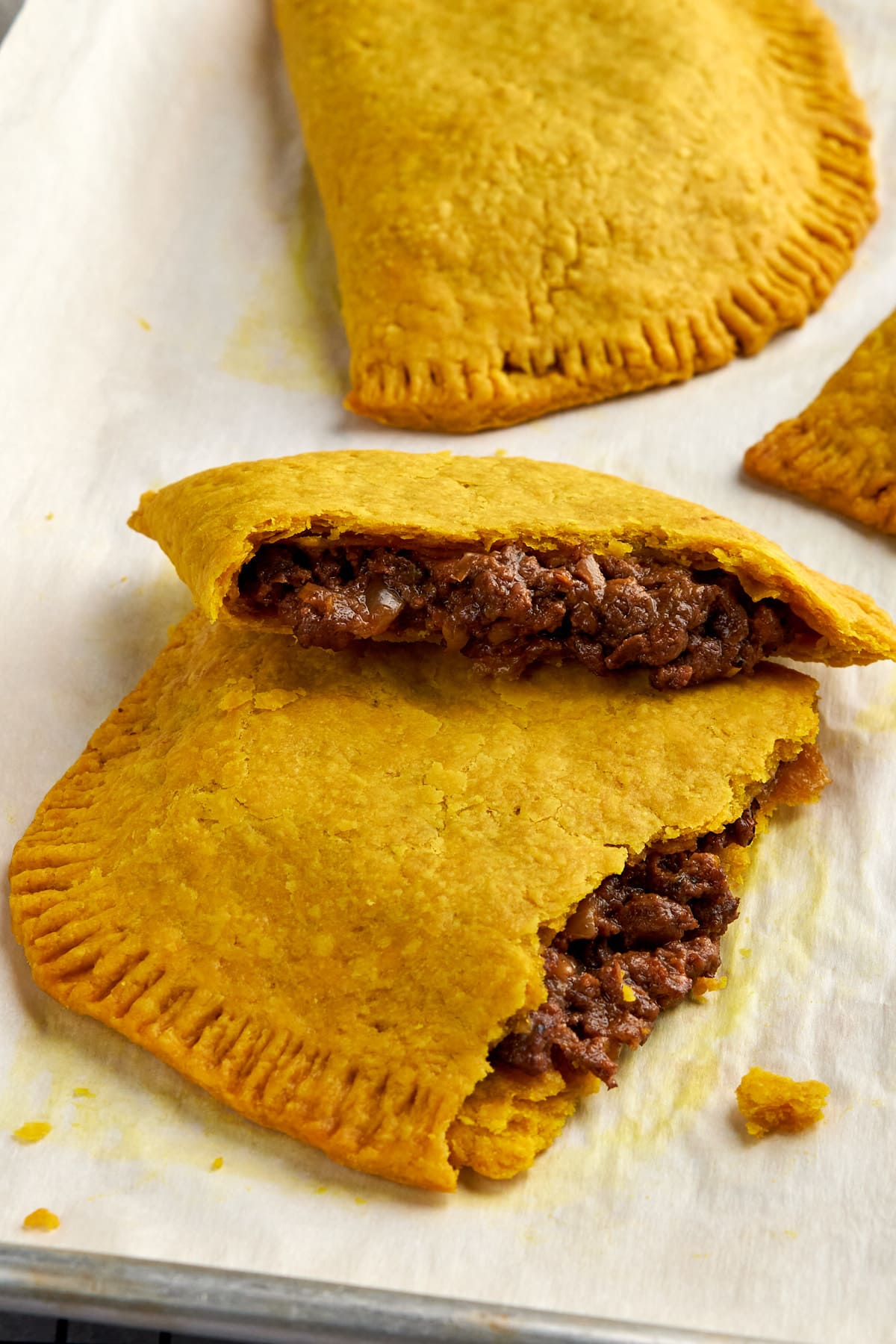 Jamaican patty cut in half on baking tray.