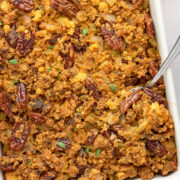 Cornbread stuffing with spoon in a casserole dish.