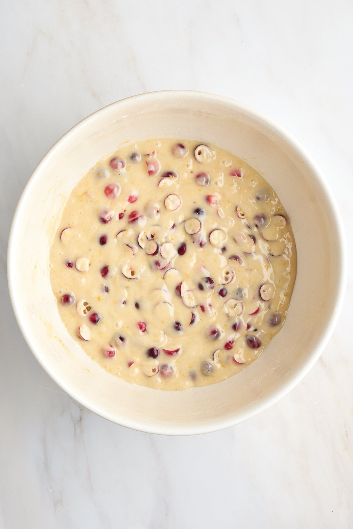 Bowl of cake batter with fresh cranberries mixed in.